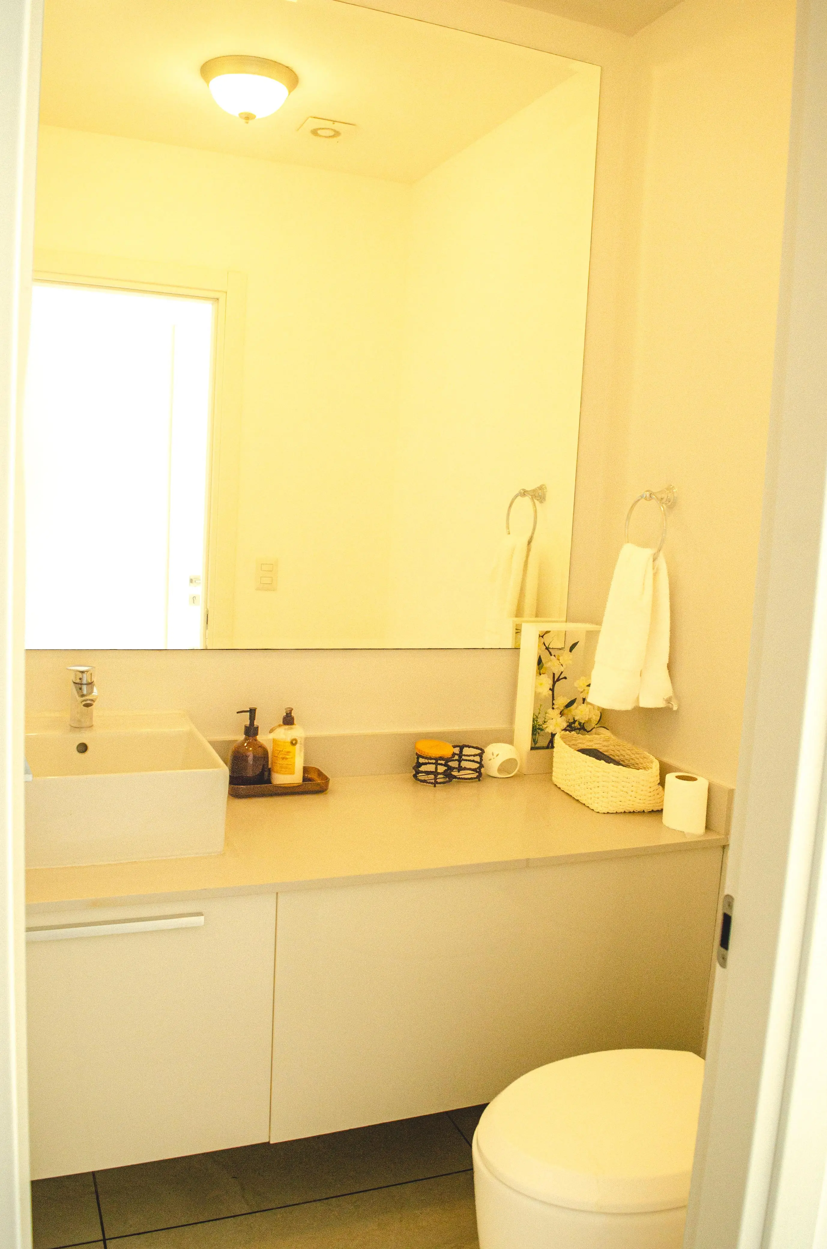 Segundo baño con lavamanos, espejo amplio y sanitario.